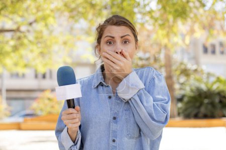 Photo for Young pretty woman covering mouth with a hand and shocked or surprised expression. presenter and microphone concept - Royalty Free Image