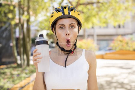 Téléchargez les photos : Young pretty woman feeling extremely shocked and surprised. bike helmet concept - en image libre de droit