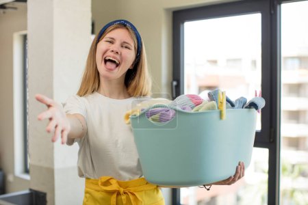 Foto de Joven bonita mujer sonriendo felizmente y ofreciendo o mostrando un concepto. concepto de lavandería y lavado de ropa - Imagen libre de derechos