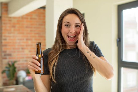Photo for Pretty woman feeling happy and astonished at something unbelievable. beer bottle - Royalty Free Image