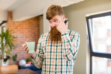 Photo for Red hair man red hair man looking surprised, realizing a new thought, idea or concept with a coffee mug - Royalty Free Image