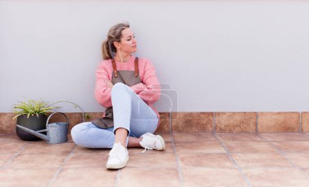 Photo for Pretty young woman gardering and sitting on the floor outdoors - Royalty Free Image