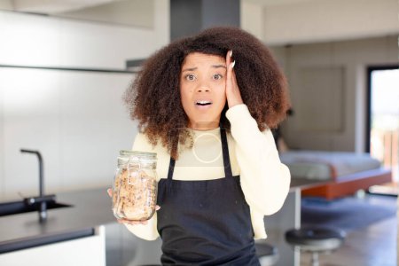Photo for Pretty afro black woman feeling extremely shocked and surprised. homemade cookies concept - Royalty Free Image