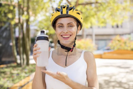 Téléchargez les photos : Young pretty woman smiling cheerfully, feeling happy and showing a concept. bike helmet concept - en image libre de droit