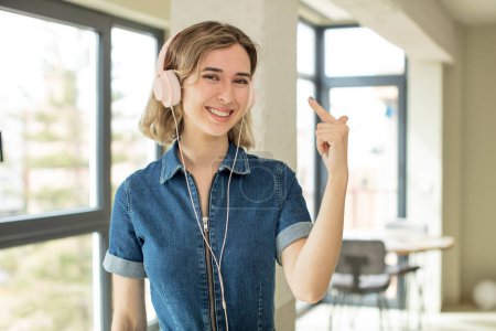 Photo for Pretty woman smiling cheerfully, feeling happy and showing a concept. headphones and music concept - Royalty Free Image