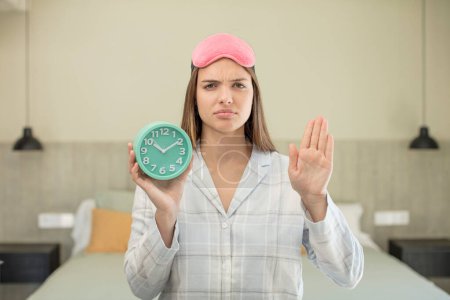 Photo for Young pretty woman looking serious showing open palm making stop gesture. alarm clock concept - Royalty Free Image