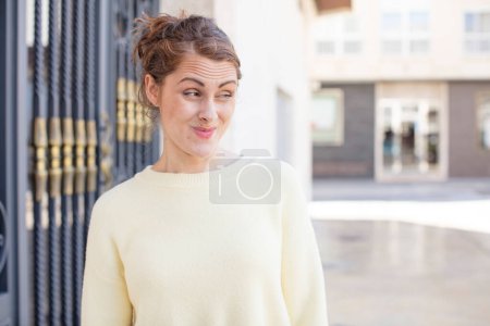 Photo for Pretty young woman wondering, thinking happy thoughts and ideas, daydreaming, looking to copy space on side - Royalty Free Image