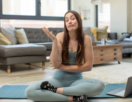 Téléchargez les photos : Jeune femme adulte pratiquant le yoga souriant fièrement et en toute confiance, se sentant heureuse et satisfaite et montrant un concept sur l'espace de copie - en image libre de droit