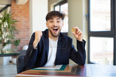 Foto de Joven hombre guapo sentirse sorprendido, riendo y celebrando el éxito. concepto de dinero virtual - Imagen libre de derechos