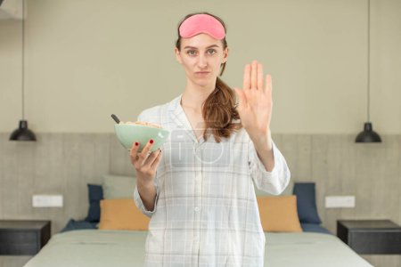 Photo for Looking serious showing open palm making stop gesture. pajamas or night wear concept - Royalty Free Image