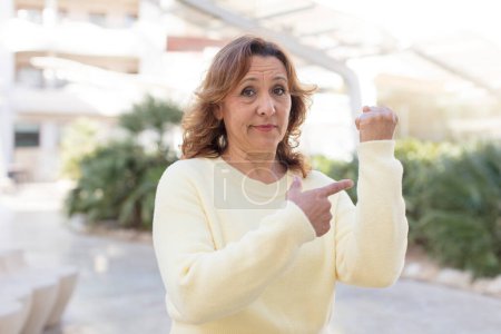 Photo for Middle age woman looking impatient and angry, pointing at watch, asking for punctuality, wants to be on time - Royalty Free Image
