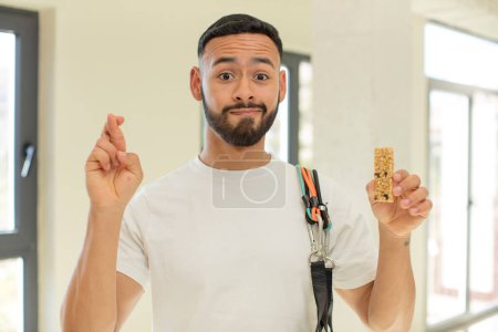 Photo for Arab handsome man arab man crossing fingers and hoping for good luck.  fitness and cereal bar concept - Royalty Free Image