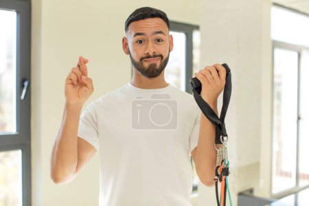 Téléchargez les photos : Beau arabe homme arabe croisant les doigts et espérant bonne chance. concept de fitness - en image libre de droit