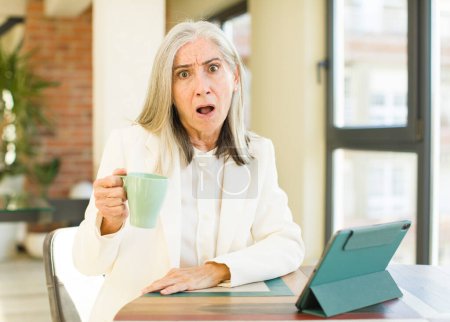 Téléchargez les photos : Senior jolie femme se sentant extrêmement choqué et surpris avec un écran tactile - en image libre de droit