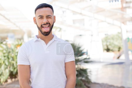 Photo for Young handsome man with cheerful, carefree, rebellious attitude, joking and sticking tongue out, having fun - Royalty Free Image