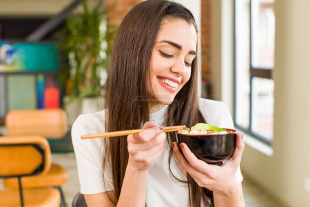 Foto de Mujer joven y bonita comiendo fideos chinos ramen bowl. casa de diseño de interiores - Imagen libre de derechos