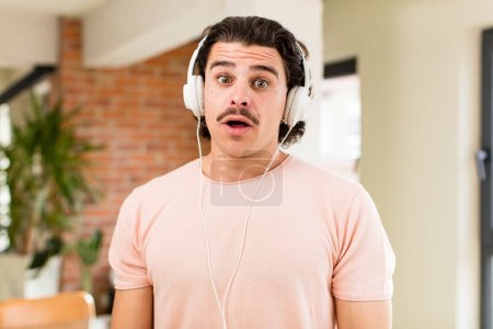 Foto de Joven hombre guapo escuchando música con auriculares en el interior de casa - Imagen libre de derechos