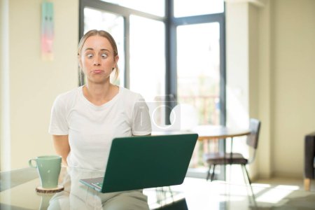 Foto de Mujer guapa caucásica con un ordenador portátil sentirse estresado, infeliz y frustrado, tocando la frente y sufriendo migraña de dolor de cabeza severo - Imagen libre de derechos