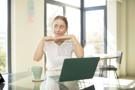 Téléchargez les photos : Caucasienne jolie femme avec un ordinateur portable se sentant réfléchi, se demandant ou imaginant des idées, rêvant et regardant vers le haut pour copier l'espace - en image libre de droit