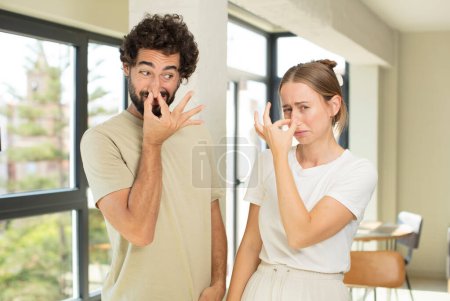 jeune couple adulte se sentant dégoûté, tenant le nez pour éviter de sentir une puanteur nauséabonde et désagréable