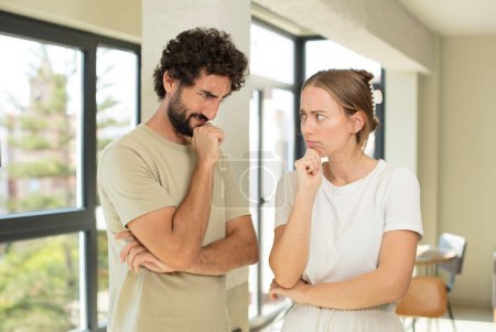 Photo for Young adult couple feeling confused or doubting, concentrating on an idea, thinking hard, looking to copy space on side - Royalty Free Image