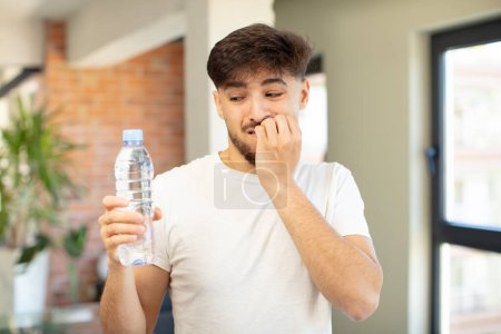 Photo for Young handsome man feeling scared, worried or angry and looking to the side. water bottle concept - Royalty Free Image