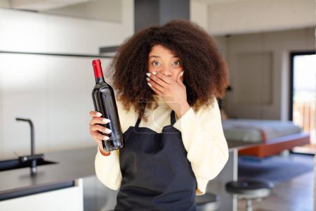 Photo for Pretty afro black woman covering mouth with a hand and shocked or surprised expression. wine bottle concept - Royalty Free Image