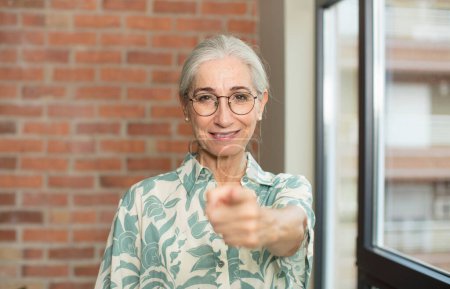 Téléchargez les photos : Senior jolie femme pointant vers la caméra avec un sourire satisfait, confiant et amical, vous choisissant - en image libre de droit