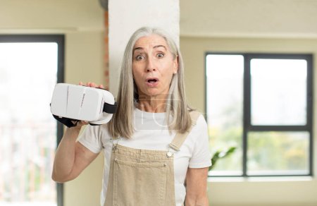 Photo for Pretty senior woman feeling extremely shocked and surprised. with vr goggles - Royalty Free Image
