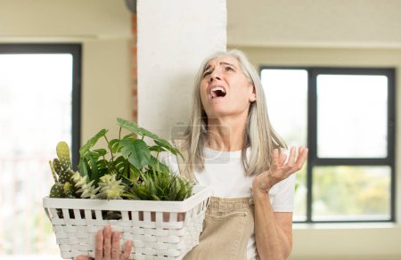 Foto de Una mujer mayor gritando con las manos en alto. concepto de jardinero - Imagen libre de derechos