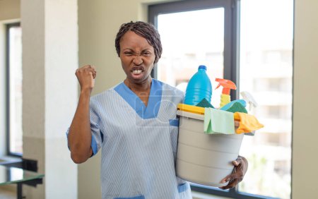 Photo for Black afro woman looking angry, annoyed and frustrated with clean products. housekeeper concept - Royalty Free Image