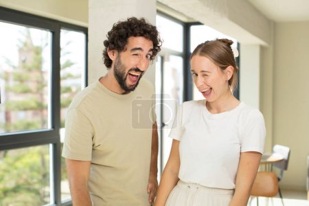 Foto de Joven pareja adulta mirando feliz y amigable, sonriendo y guiñando un ojo a usted con una actitud positiva - Imagen libre de derechos
