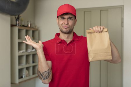 Photo for Young handsome man shrugging, feeling confused and uncertain. delivery man concept - Royalty Free Image