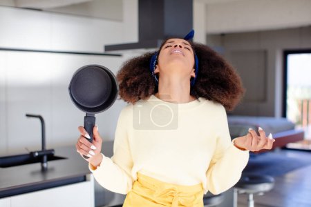 Photo for Pretty afro black woman screaming with hands up in the air. home chef concept - Royalty Free Image