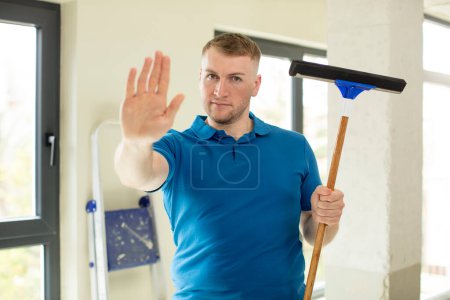 Photo for Looking serious showing open palm making stop gesture. windows washer - Royalty Free Image