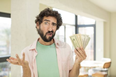 Photo for Crazy bearded man shrugging, feeling confused and uncertain. dollar banknotes concept - Royalty Free Image