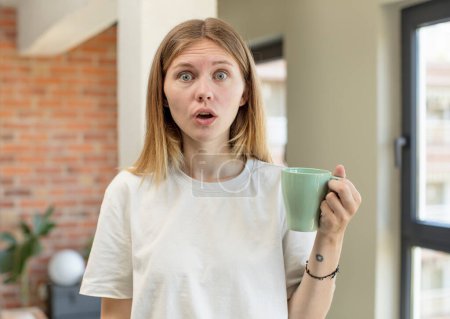 Photo for Young pretty woman feeling extremely shocked and surprised. coffee cup concept - Royalty Free Image