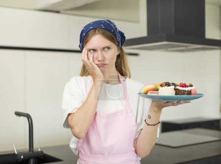 Photo for Young pretty woman feeling bored, frustrated and sleepy after a tiresome. home made cakes concept - Royalty Free Image