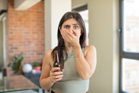 Photo for Young woman covering mouth with a hand and shocked or surprised expression. beer bottle - Royalty Free Image