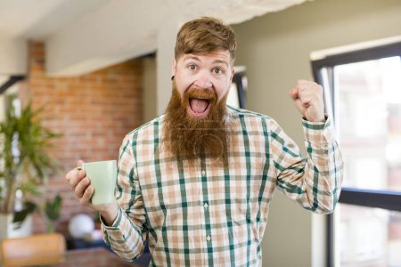 Photo for Red hair man red hair man feeling shocked,laughing and celebrating success with a coffee mug - Royalty Free Image