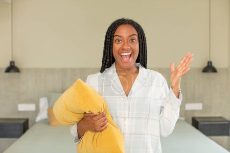 Téléchargez les photos : Afro noir femme se sentant heureux et étonné de quelque chose d'incroyable. concept de repos et vêtements de nuit - en image libre de droit