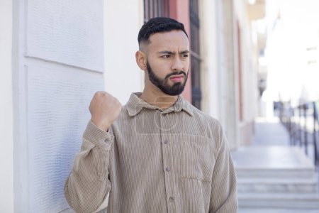 Téléchargez les photos : Jeune homme beau regard confiant, en colère, fort et agressif, avec les poings prêts à se battre en position de boxe - en image libre de droit