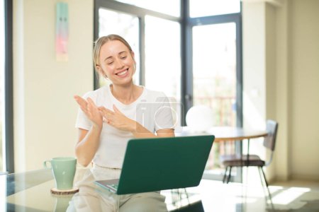 Photo for Caucasian pretty woman with a laptop feeling happy and successful, smiling and clapping hands, saying congratulations with an applause - Royalty Free Image