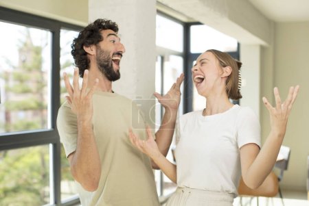 Téléchargez les photos : Jeune couple adulte heureux, étonné, chanceux et surpris, célébrer la victoire avec les deux mains en l'air - en image libre de droit