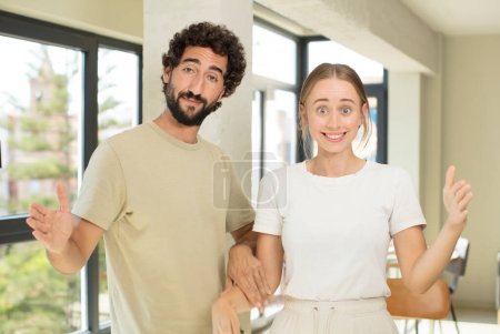 Photo for Young adult couple holding an object with both hands on copy space, showing, offering or advertising an object - Royalty Free Image