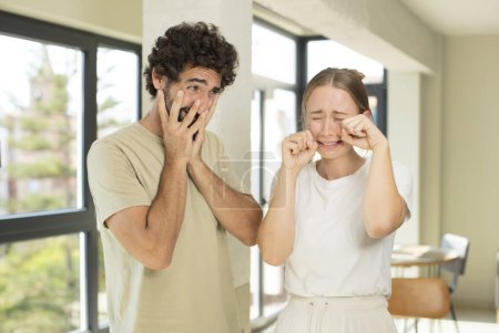 Photo for Young adult couple looking desperate and frustrated, stressed, unhappy and annoyed, shouting and screaming - Royalty Free Image