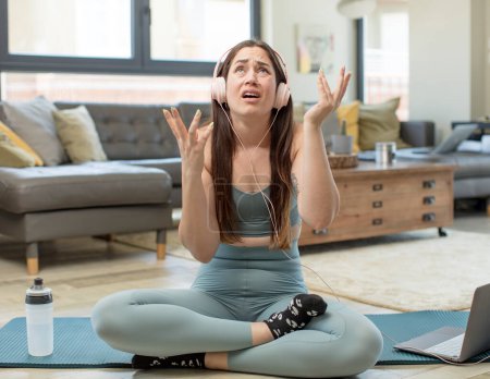 Photo for Young adult woman practicing yoga looking desperate and frustrated, stressed, unhappy and annoyed, shouting and screaming - Royalty Free Image