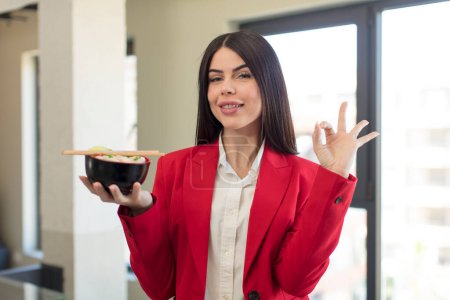 Photo for Pretty young woman feeling happy, showing approval with okay gesture. japanese ramen bowl concept - Royalty Free Image