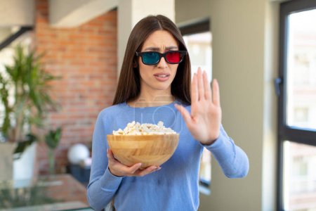Photo for Looking serious showing open palm making stop gesture. popcorns and movie concept - Royalty Free Image