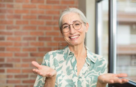 Téléchargez les photos : Senior jolie femme souriant joyeusement donnant une accolade chaleureuse, amicale et aimante bienvenue, se sentant heureux et adorable - en image libre de droit